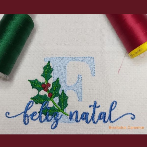 Pano de cozinha com Feliz Natal e um ramo de azevinho bordados.