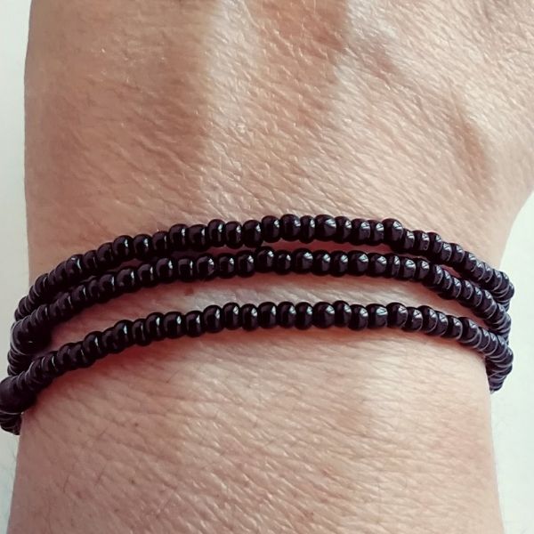 Conjunto de três pulseiras de missangas pretas.