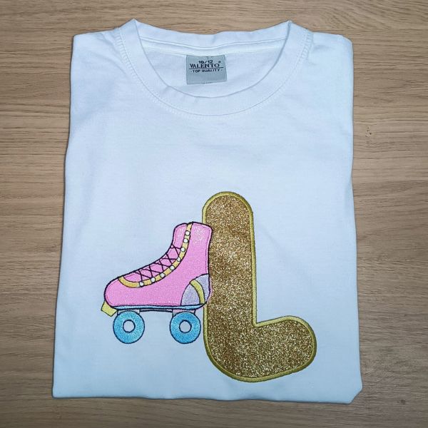 T-shirt criança branca com aplicação de vinil têxtil e bordado em inicial L e patim.