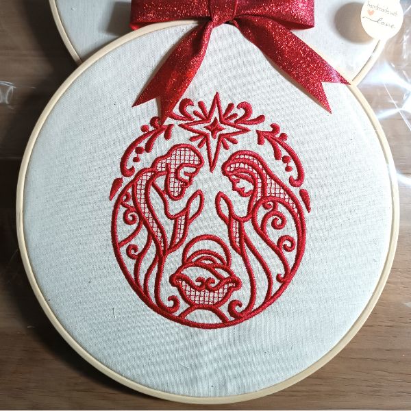 Bastidor com o bordado vermelho da Sagrada Família.