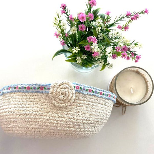 Cesta redonda, em cordão de algodão cru decorada na parte superior com fita ás flores.
