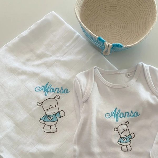 Conjunto personalizado composto por: fralda e body  bordados com rinoceronte e nome  +  cesta de corda cujo exterior tem barbante azul num tom muito semelhante ao do bordado.