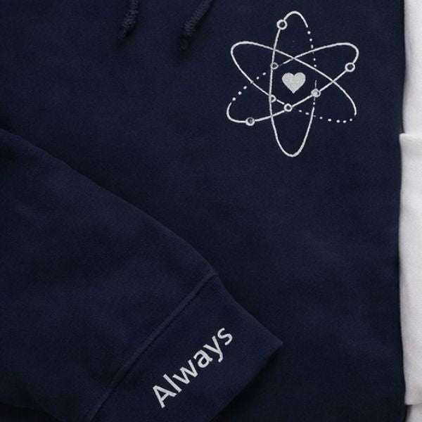 Pormenor do bordado átomo do amor e a palavra Always.