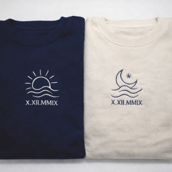 Camisola bordada com o Sol ou a Lua e a data em numeração romana.