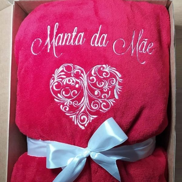 Manta vermelha com coração bordado a branco, assim como "Manta da Mãe".
