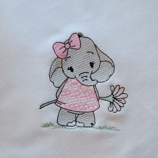 Pormenor do bordado realizado numa fralda de uma elefante a segurar uma flor.