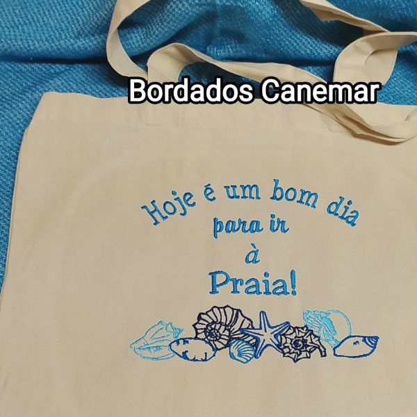 Saco com bordado "Hoje é um bom dia para ir à praia" e alguns búzios, conchas e estrela do mar.