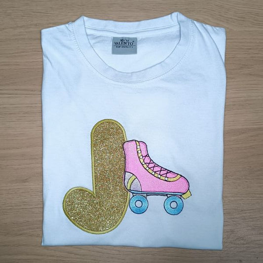 T-shirt criança branca com aplicação de vinil têxtil e bordado em inicial J e patim.