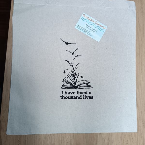 Tote bag bordado com livro aberto "I have lived a thousand lives".