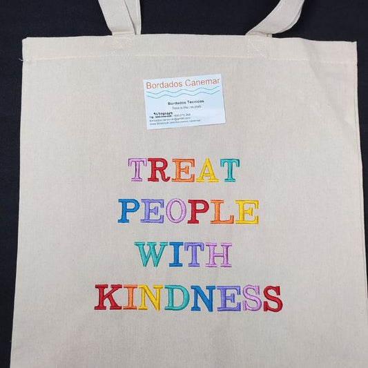 Tote bag com a frase "Treat people with kindness"  bordada com letras em várias cores.