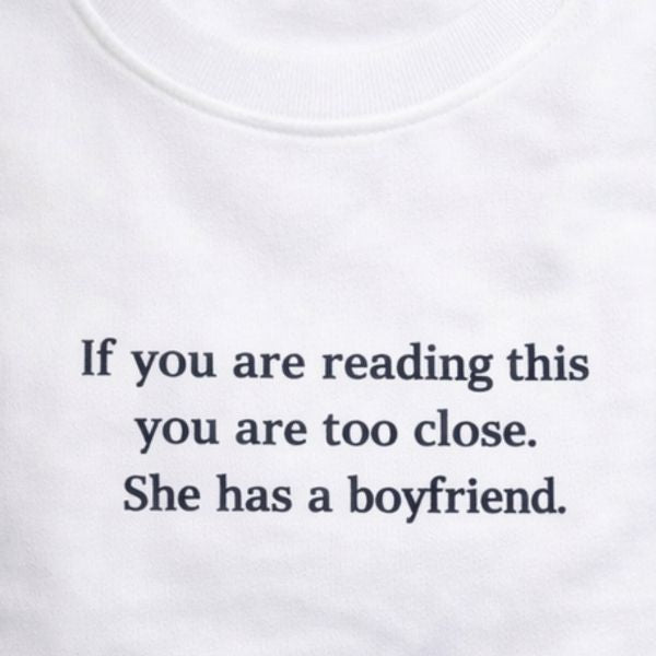 Camisola com bordado para ela, com a frase "Se está a ler isto é porque está demasiado perto. Ela tem namorado".