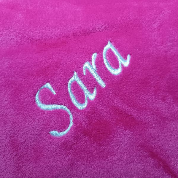Manta rosa fuchsia com o nome Sara bordado a branco.