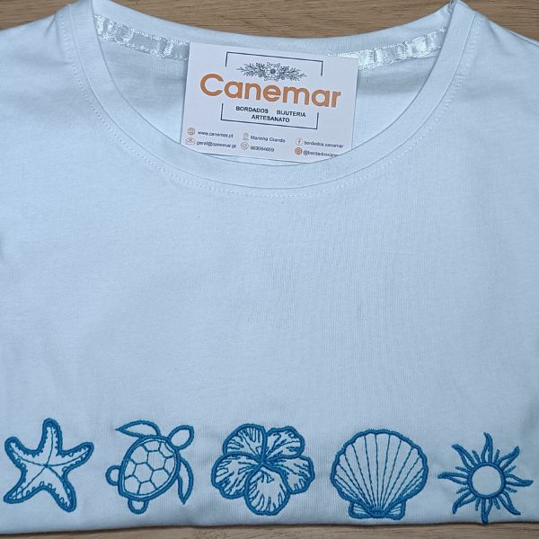 T-shirt branca bordada a azul com estrela do mar, tartaruga, hibisco, concha e sol.
